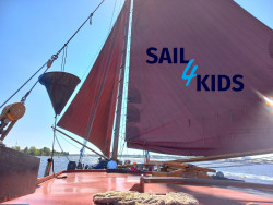 Blick über das Deck eines Traditionsseglers mit Sail4kids-Logo auf dem Großsegel