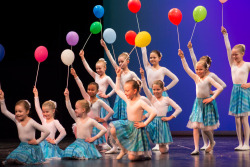 Tanzende Mädchen mimt Luftballons auf einer Bühne